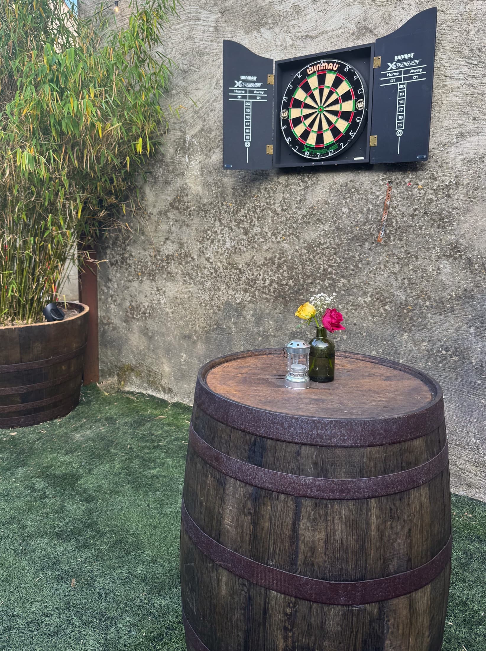 A barrel table and dartboard in the courtyard